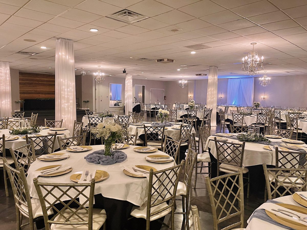 St. Louis ballroom set for a wedding reception with gold chairs, round tables and chandeliers